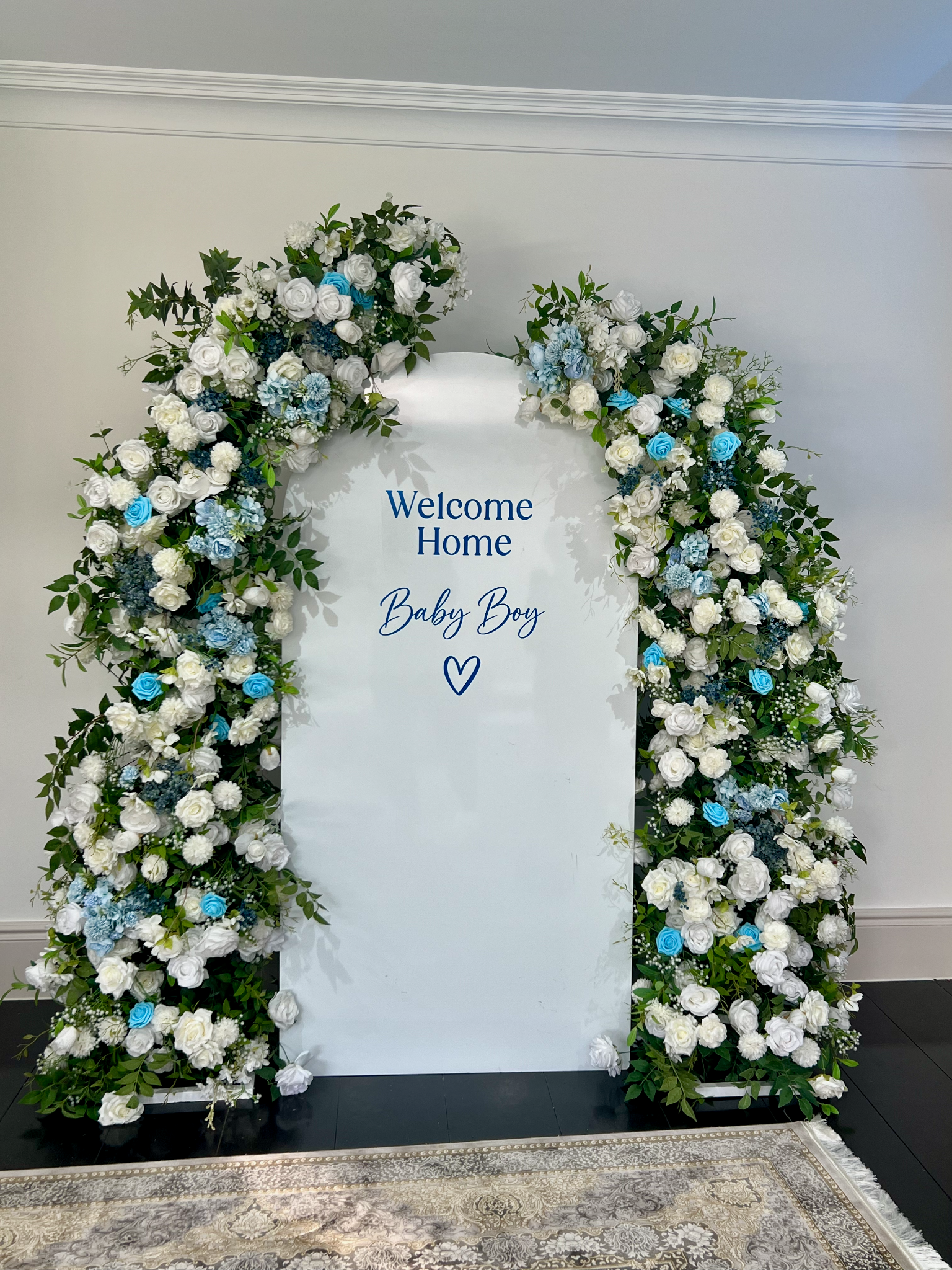 Blue and white floral arch with a Welcome Home Baby Boy backdrop by Nour Occasions