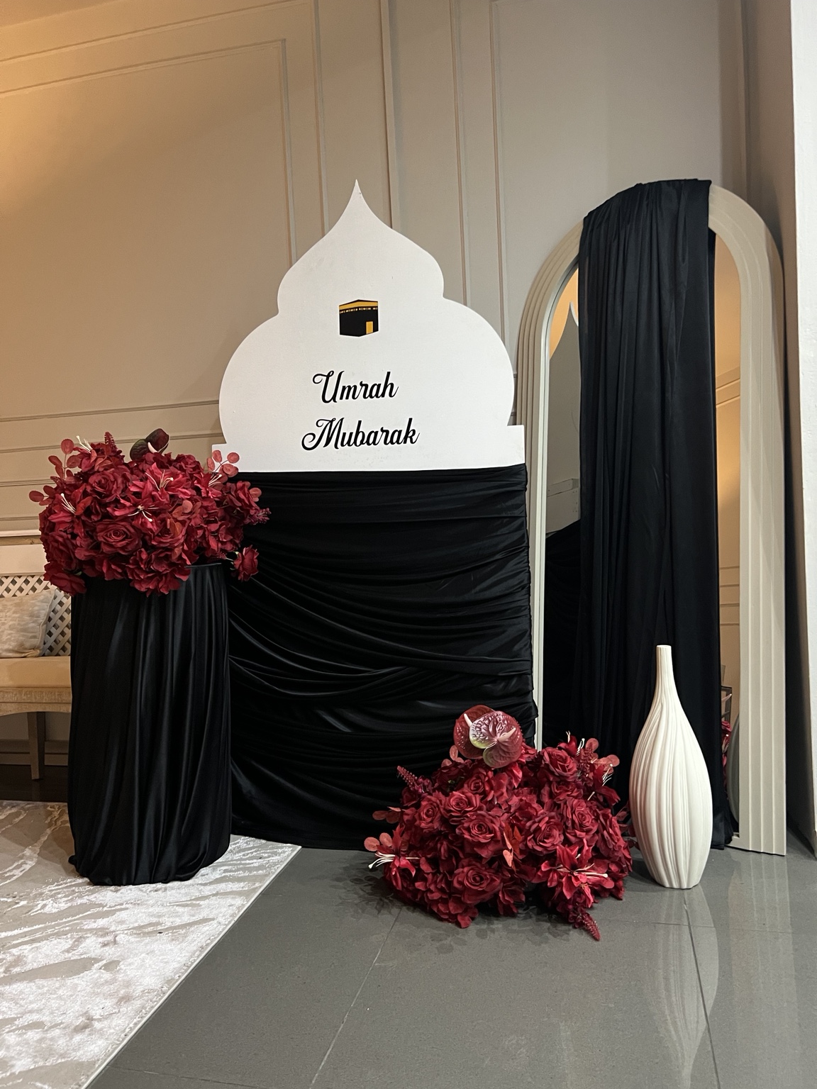 Black draping, burgundy flowers and a personalised Umrah Mubarak board by Nour Occasions